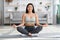 Domestic Yoga. Happy young asian woman meditating at home in lotus position