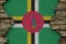 Dominica flag depicted in paint colors on old stone wall closeup. Textured banner on rock wall background