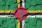 Dominica flag depicted in paint colors on old stone wall closeup. Textured banner on rock wall background