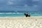 Dominican policeman on a black horse patrols the beach area.