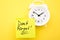 Don`t forget- reminder on sticker on white alarm clock isolated on yellow background