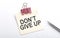 Don`t Give Up text on sticker with pen on the white background