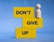 Don't give up text on wooden blocks with wooden doll standing at the edge. Motivational concept