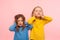 We don`t want to listen! Portrait of two naughty disobedient little girls covering ears with hands, ignoring parental advice