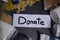 `Donate` sign handwritten with black letters. A pile of food supplies on a grey table. Food donation concept. Context of