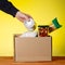 Donation box with food and hands of a volunteer. Macaroni, buckwheat, canned food, oil filling in a box. Volunteer assistance to