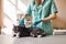 Almost done! Young female veterinarian in work uniform making an injection to a black and fluffy cat with scared eyes