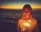 Dont let anyone dim your light from within. Portrait of a young woman holding a sparkler at the beach at night.