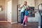 They dont need much to have fun. a happy little girl balancing on her fathers feet while they walk around in the kitchen