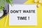 Dont Waste Time written with alarm clock and Notebook on yellow background. Business concept