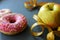 Donut and apple healthy food choices on wooden board