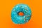 Donut blue with sprinkles isolated on orange background, close-up