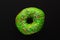 Donut green with sprinkles isolated on black background, close-up