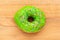 Donut green with sprinkles isolated on wooden background