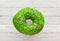 Donut green with sprinkles isolated on wooden background, close-up