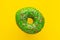 Donut green with sprinkles isolated on yellow background, close-up