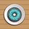 Donut with mint glaze on a white plate on the wood background.
