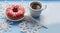 Donut with pink icing with snowflake and coffee on blue background