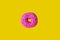Donut with pink icing on a yellow background top view. Junk food. Sweets, pastries