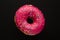 Donut pink with sprinkles isolated on black background, close-up