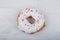 Donut with white glaze on white wooden background