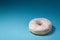 Donut with white icing isolated on blue background