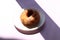 Donut on a white saucer on a purple background in the sun, top view, place for the inscription