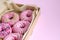 Donuts close-up with pink icing lie in an open box on a pink background. Horizontal background, selective focus