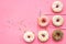 Donuts decorated icing and sprinkles on pink background top view copy space pattern