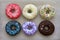 Donuts of different colors on cardboard, view from above