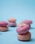 Donuts with different colors stacked into one isolated blue background.