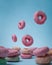 Donuts with different colors stacked into one isolated blue background.