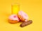 The donuts and fresh orange juice on yellow background