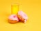 The donuts and fresh orange juice on yellow background