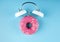 Donuts glaze with alarm clock alarm on blue background. Donuts alarm clock