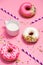 Donuts with icing and milk on pastel pink background. Sweet donuts.