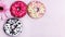 Donuts with icing on pastel pink background. Sweet donuts. Candies on wooden background. Party food concept with copy space.