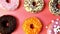 Donuts with icing on pastel pink background. Sweet donuts. top view assorted with various chocolate glazed and sprinkles