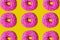 Donuts with pink icing on a yellow background top view. Junk food. Sweets, pastries