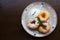 Donuts on the plate. Three donuts with powdered sugar, mint leaf and sour cream on the plate. Dark wooden background.