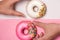 Donuts, sweetmeats candy on pink background. Hand holds donut.