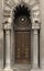 The door of ancient building with columns and rose window above it.