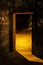 The door arch in a shadowed brick wall close-up , behind which a lit street is visible