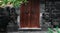 Door or gate to enter into traditional balinese garden architecture detail. Wooden Indonesian gate guarded by stone statues.