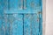 Door hinge on an old wooden door with blue chipped paint