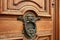 A door knocker in the shape of a lion adorns an old door