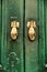 Door knockers with hand shape on green wooden door