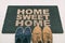 Door mat Shoes at front entrance of condo apartment. Written welcome sign Home Sweet Home welcoming homeowners at new house moving