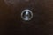 Door peephole on metal brown front door close-up