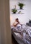 A through the door shot of a man lazing in bed on his phone